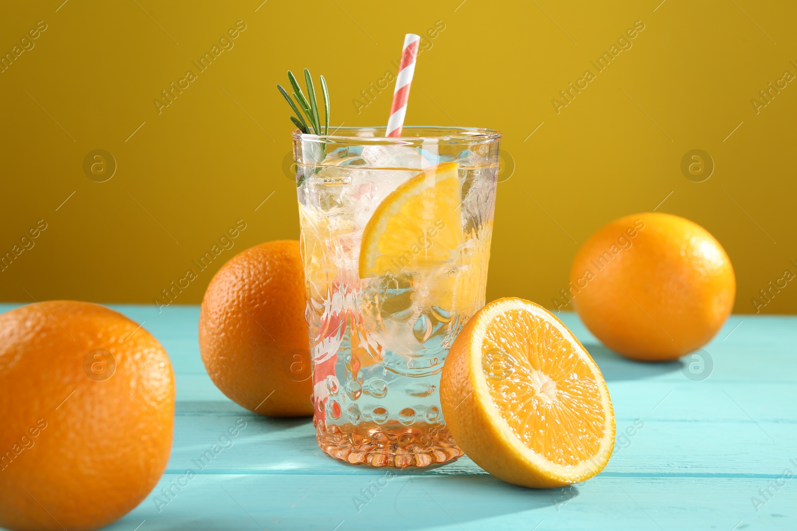 Photo of Refreshing soda water with ice and orange on light blue wooden table, closeup