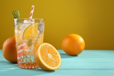 Photo of Refreshing soda water with ice and orange on light blue wooden table, closeup. Space for text