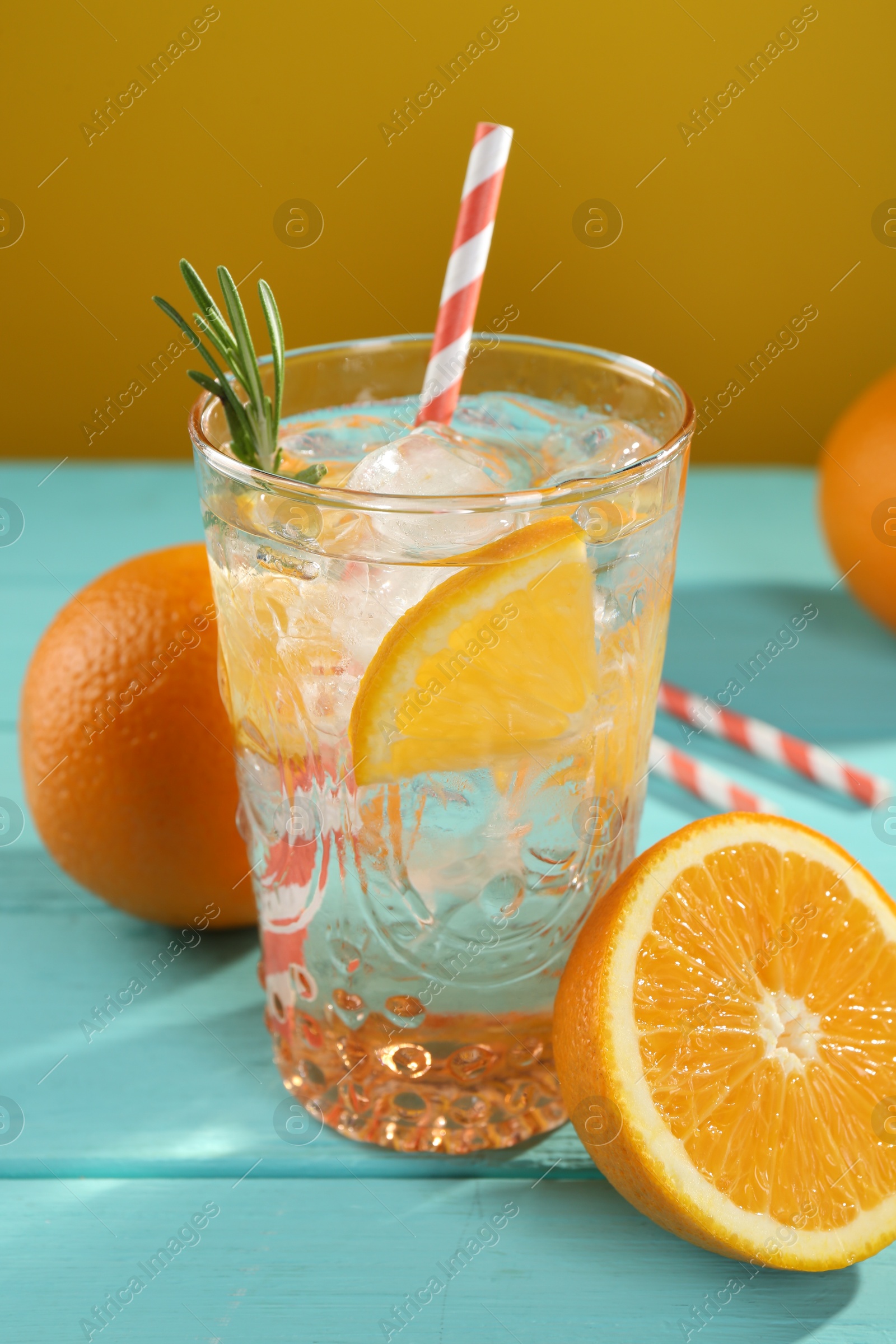 Photo of Refreshing soda water with ice and orange on light blue wooden table, closeup