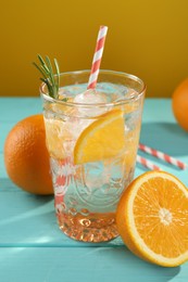 Photo of Refreshing soda water with ice and orange on light blue wooden table, closeup