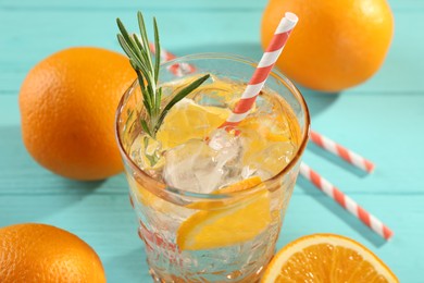 Photo of Refreshing soda water with ice and orange in glass on light blue table, closeup