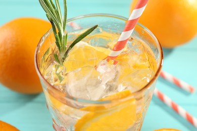 Photo of Refreshing soda water with ice and orange in glass on light blue table, closeup