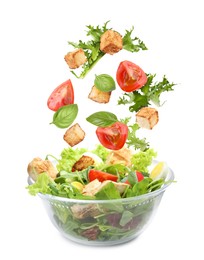 Image of Croutons and other ingredients falling into bowl of salad against white background