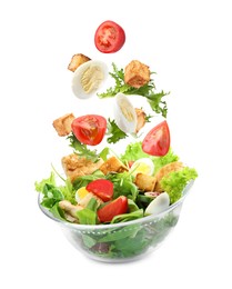 Image of Croutons and other ingredients falling into bowl of salad against white background