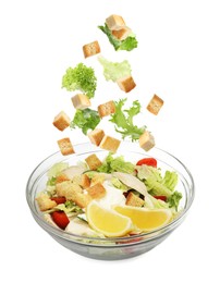 Image of Croutons and lettuce leaves falling into bowl of salad against white background