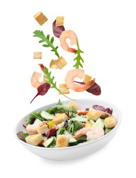 Image of Croutons and other ingredients falling into bowl of salad against white background