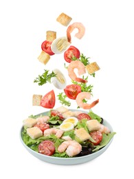 Image of Croutons and other ingredients falling into bowl of salad against white background