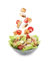 Image of Croutons and other ingredients falling into bowl of salad against white background