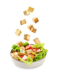 Image of Croutons falling into bowl of salad against white background