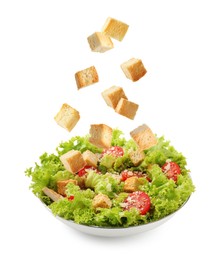 Image of Croutons falling into bowl of salad against white background