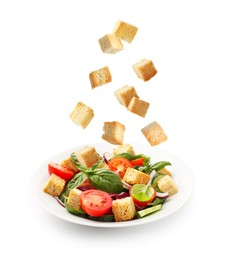 Image of Croutons falling into bowl of salad against white background