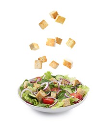 Image of Croutons falling into bowl of salad against white background