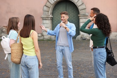 Photo of Guide with microphone and group of tourists on city street during excursion