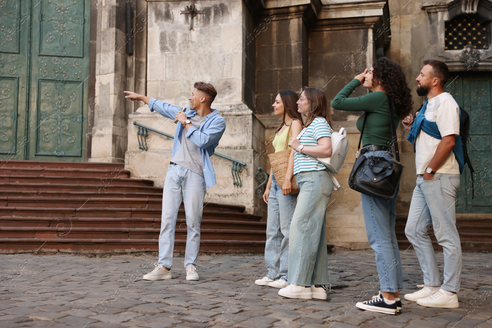 Guide with microphone and group of tourists on city street during excursion Photo of Guide with microphone and group of tourists on city street during excursion