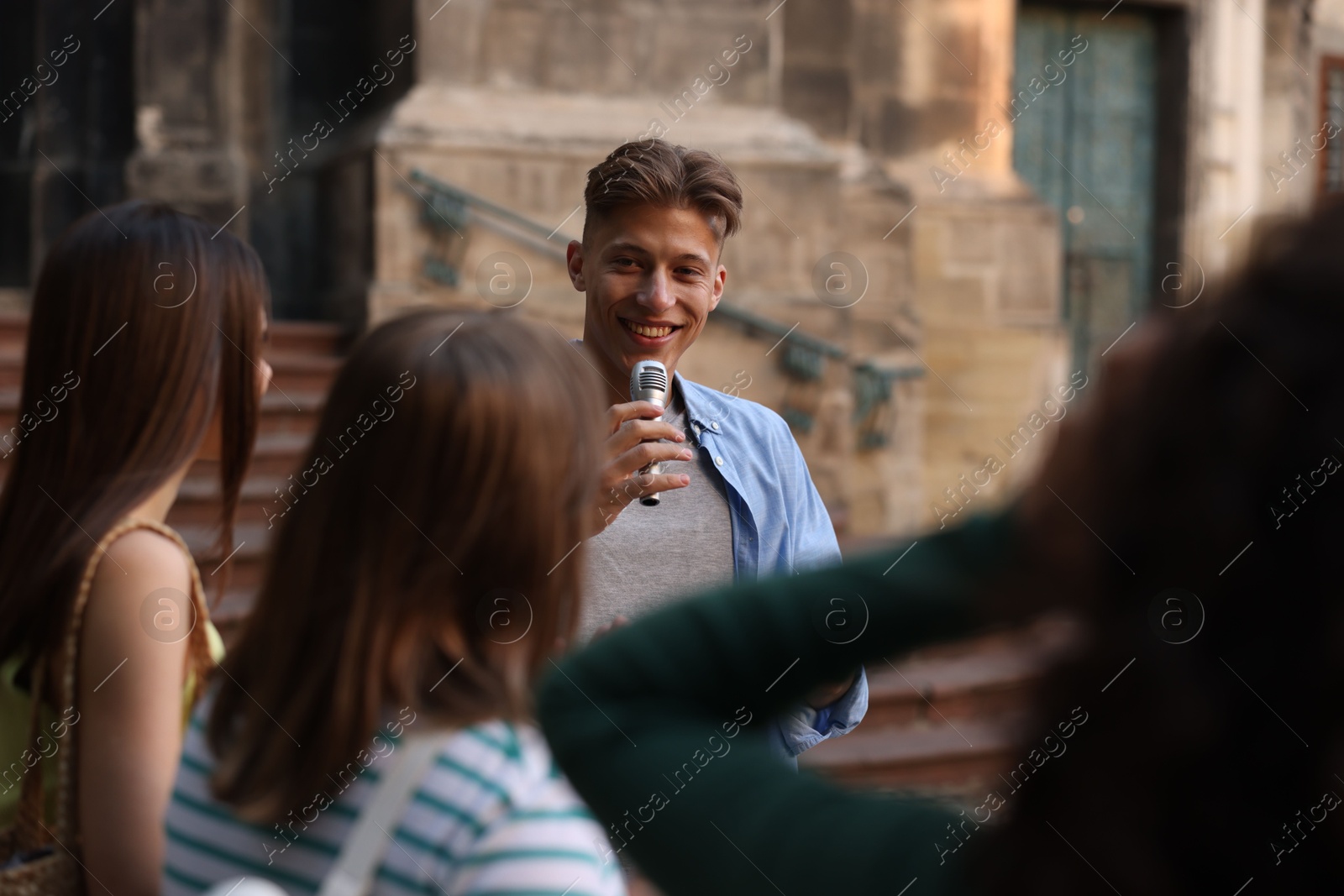 Guide with microphone and tourists on city street during excursion Photo of Guide with microphone and tourists on city street during excursion
