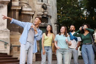Photo of Guide with microphone and group of tourists on city street during excursion