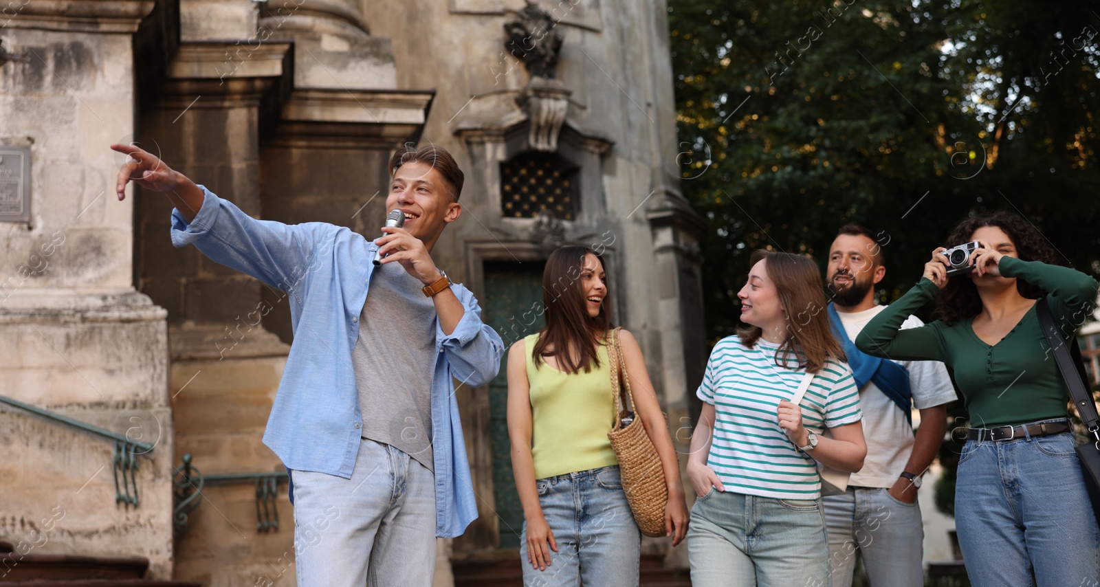 Guide with microphone and group of tourists on city street during excursion Photo of Guide with microphone and group of tourists on city street during excursion