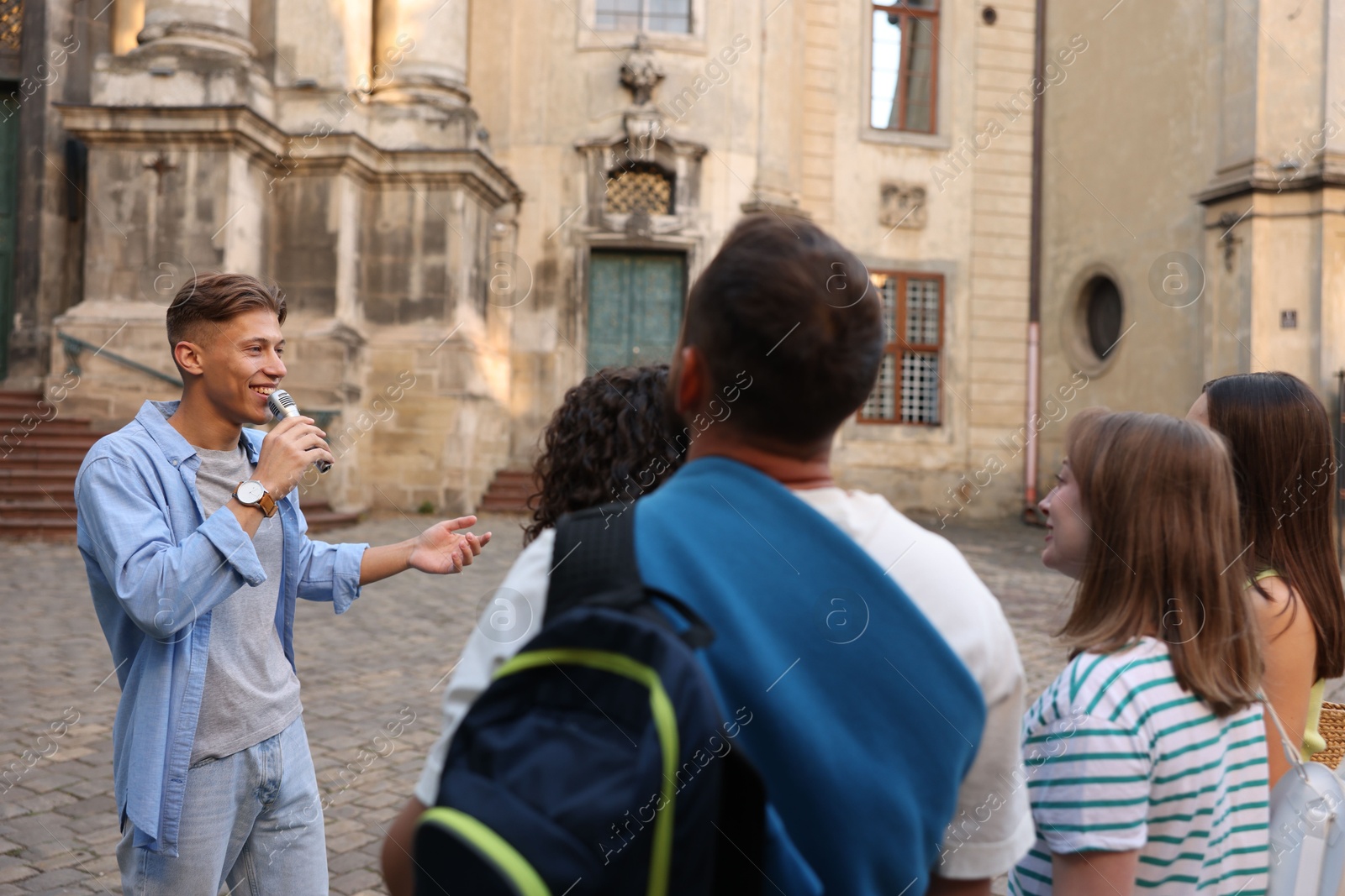 Guide with microphone and group of tourists on city street during excursion Photo of Guide with microphone and group of tourists on city street during excursion