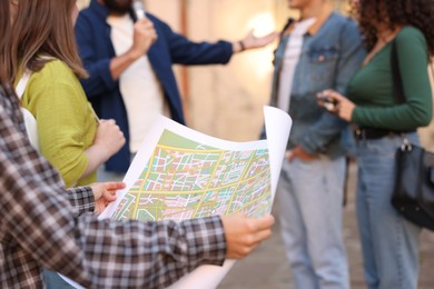 Photo of Guide with microphone and group of tourists on city street during excursion, selective focus