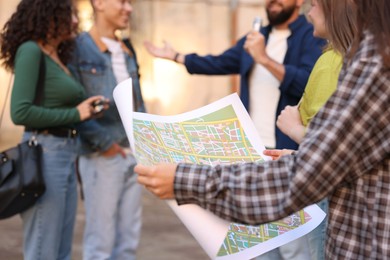 Photo of Guide with microphone and group of tourists on city street during excursion, selective focus