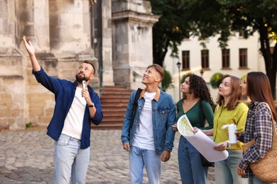 Photo of Guide with microphone and group of tourists on city street during excursion