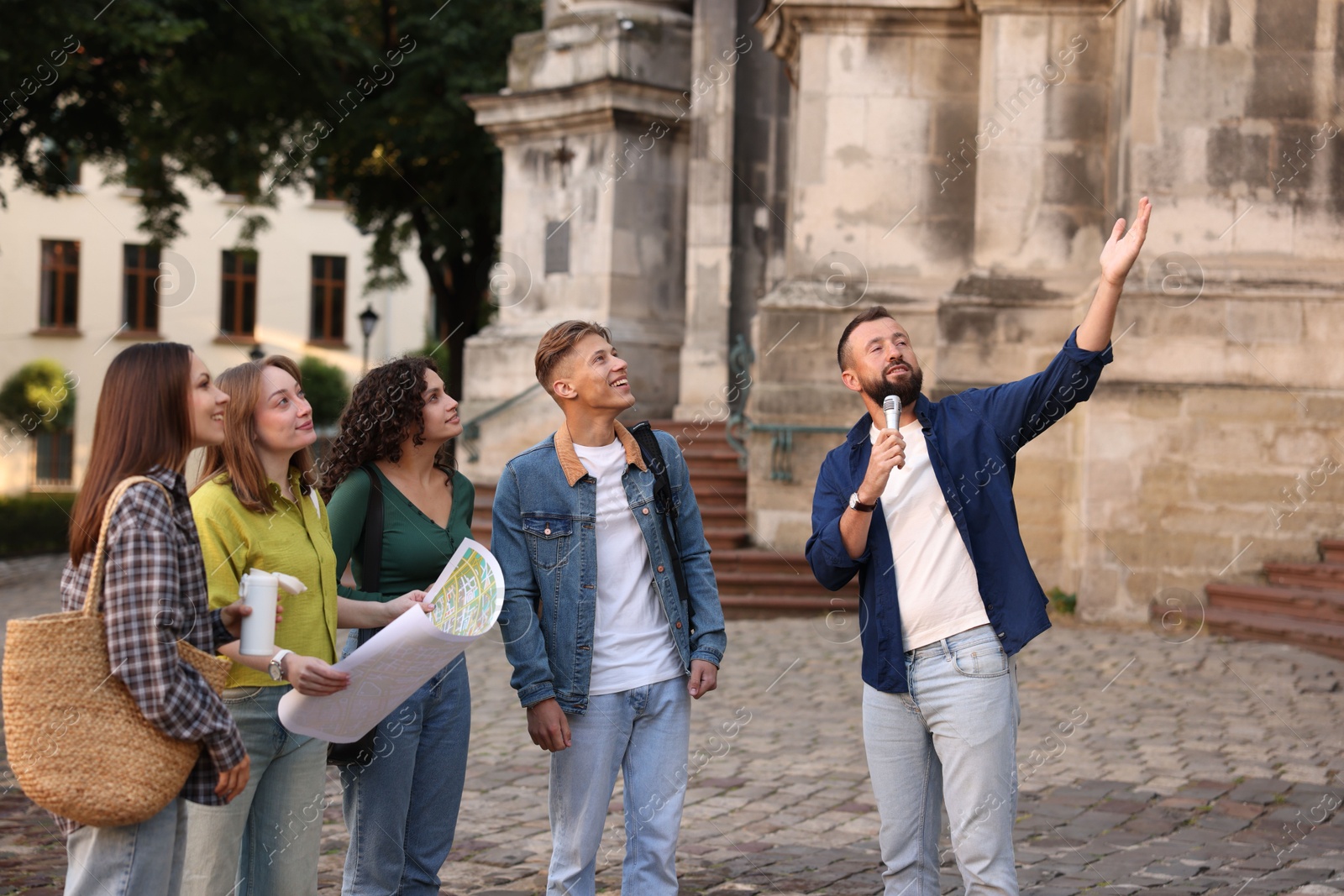 Guide with microphone and group of tourists on city street during excursion Photo of Guide with microphone and group of tourists on city street during excursion