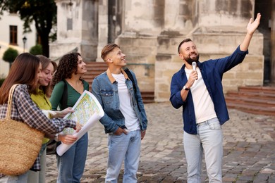 Photo of Guide with microphone and group of tourists on city street during excursion