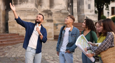 Photo of Guide with microphone and group of tourists on city street during excursion