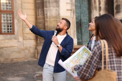 Photo of Guide with microphone and tourists on city street during excursion
