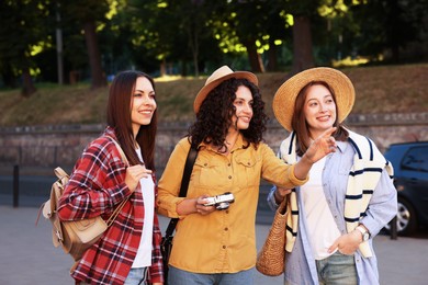 Photo of Three tourists with vintage camera walking on city street