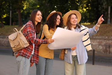 Photo of Three tourists with map walking on city street