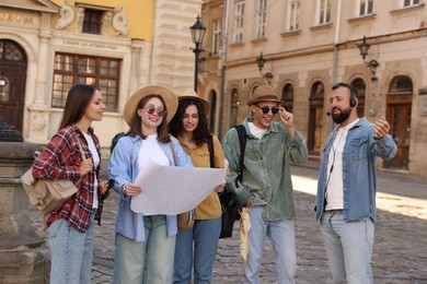 Photo of Guide with headset and group of tourists on city street during excursion