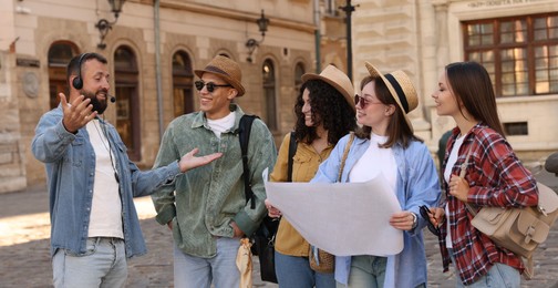 Photo of Guide with headset and group of tourists on city street during excursion