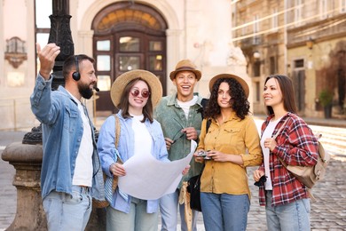 Photo of Guide with headset and group of tourists on city street during excursion