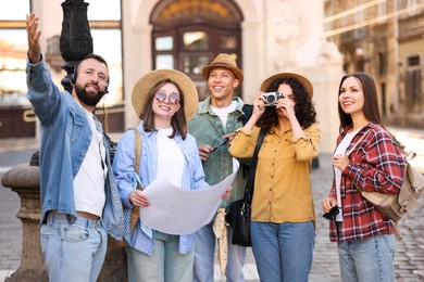 Photo of Guide with headset and group of tourists on city street during excursion