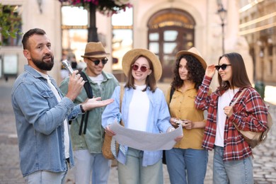 Photo of Guide with microphone and group of tourists on city street during excursion