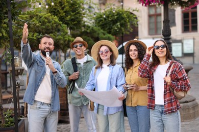 Photo of Guide with microphone and group of tourists on city street during excursion