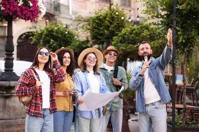 Photo of Guide with microphone and group of tourists on city street during excursion
