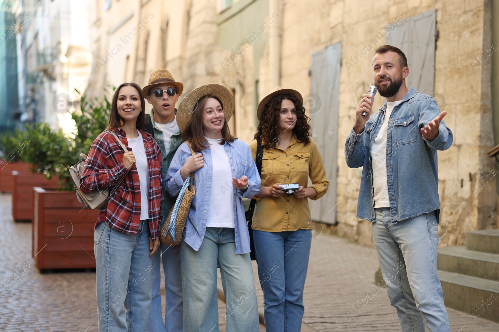Guide with microphone and group of tourists on city street during excursion Photo of Guide with microphone and group of tourists on city street during excursion