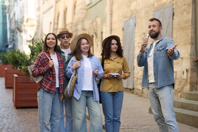 Photo of Guide with microphone and group of tourists on city street during excursion