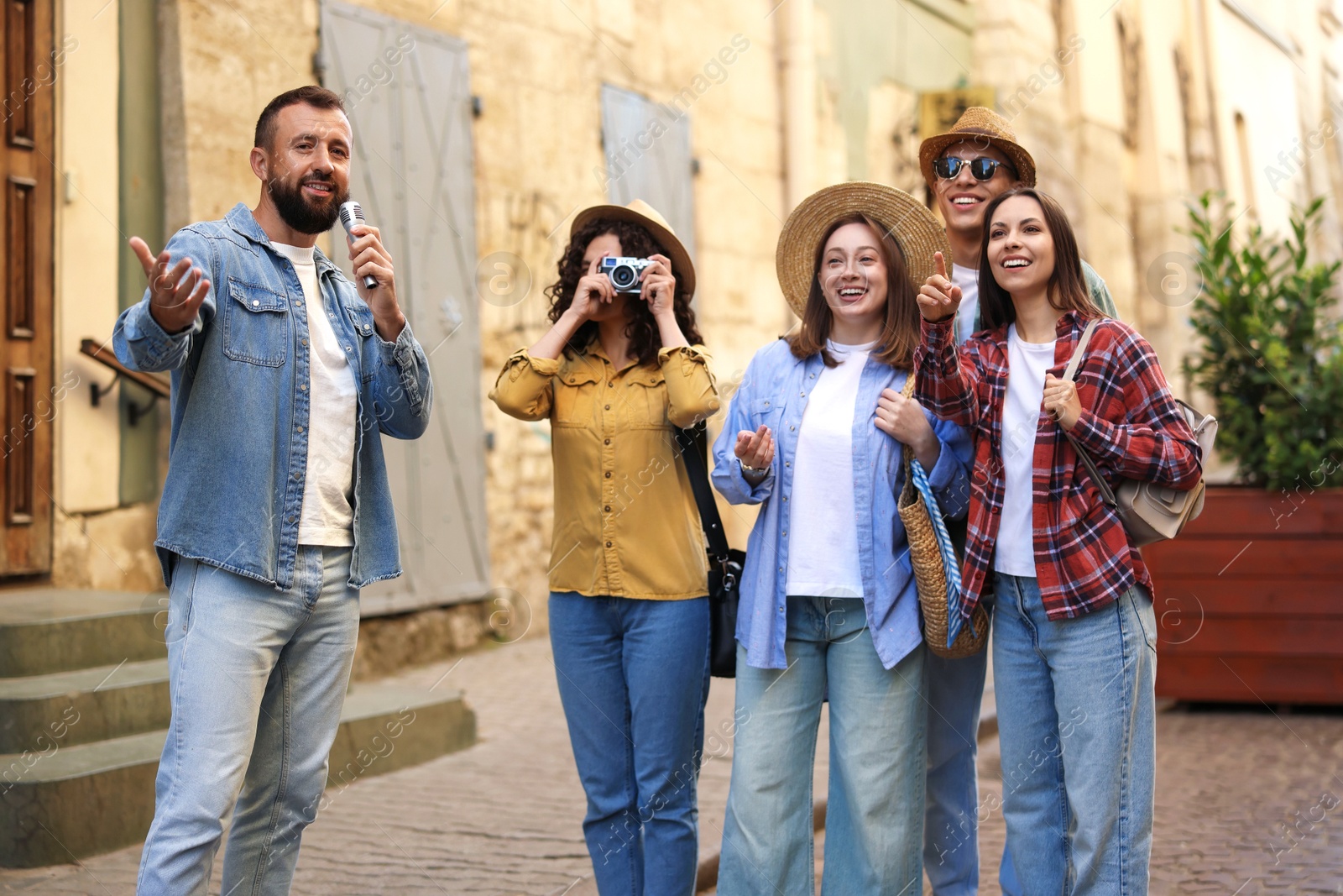 Guide with microphone and group of tourists on city street during excursion Photo of Guide with microphone and group of tourists on city street during excursion