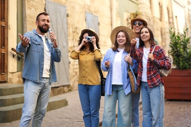 Photo of Guide with microphone and group of tourists on city street during excursion