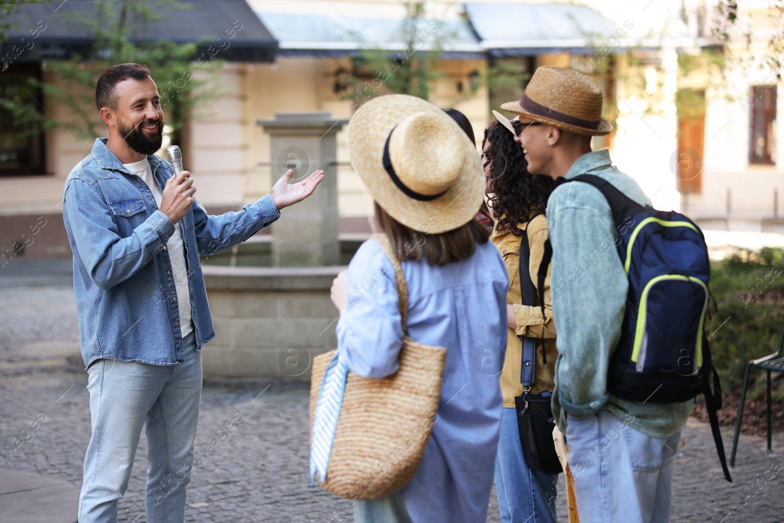 Guide with microphone and group of tourists on city street during excursion Photo of Guide with microphone and group of tourists on city street during excursion