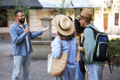Photo of Guide with microphone and group of tourists on city street during excursion