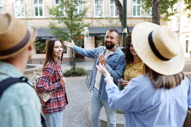Photo of Guide with microphone and group of tourists on city street during excursion