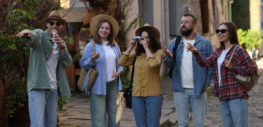 Photo of Guide with microphone and group of tourists on city street during excursion