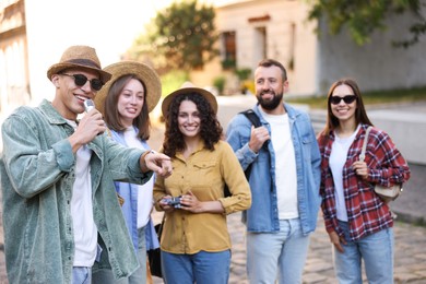 Photo of Guide with microphone and group of tourists on city street during excursion