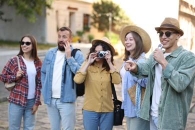 Photo of Guide with microphone and group of tourists on city street during excursion