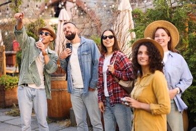 Photo of Guide with microphone and group of tourists on city street during excursion