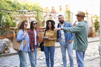 Photo of Guide with microphone and group of tourists on city street during excursion